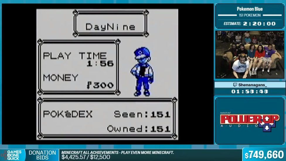 A screenshot from a Games Done Quick stream. The game is Pokémon Blue on the completion screen, showing the in-game time to read 1:56, with all 151 Pokémon caught. On the right side of the screen is Shenanagans, a young gamer, and behind him a couch of people watching for commentary. Behind them is a larger audience.