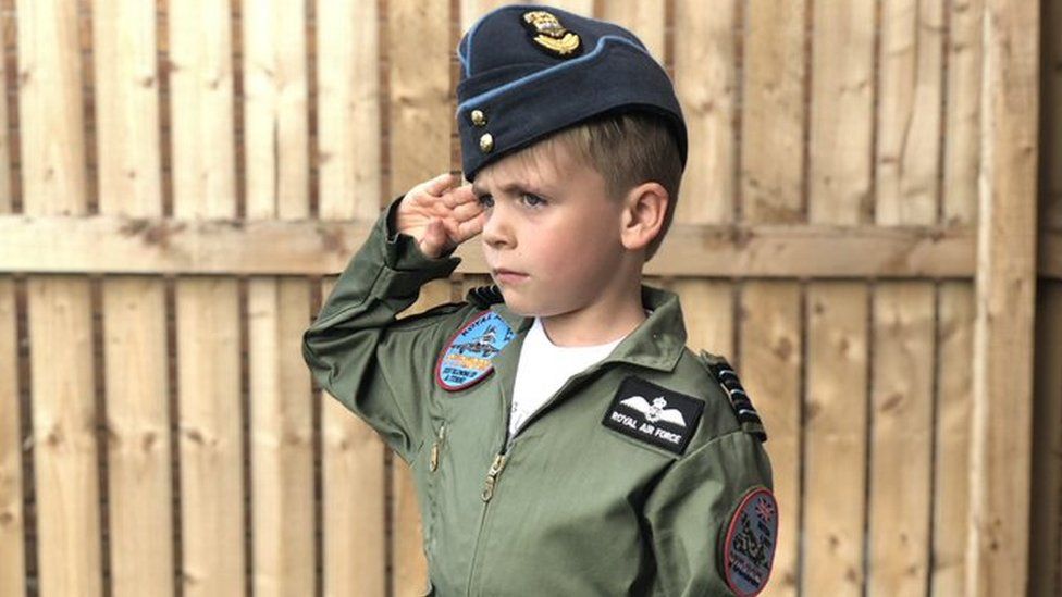 Boy saluting dressed in a flying suit
