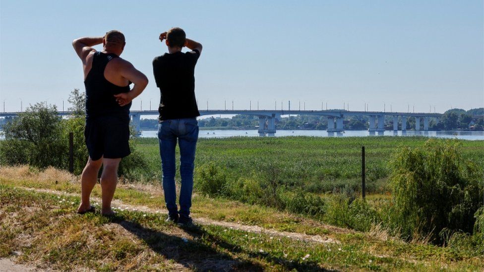 Men look over at the Antonivskiy Bridge, 27 July