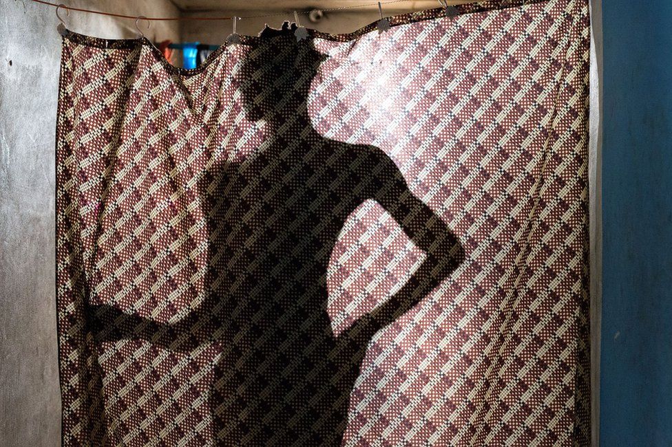 A silhouette of a person standing behind a curtain