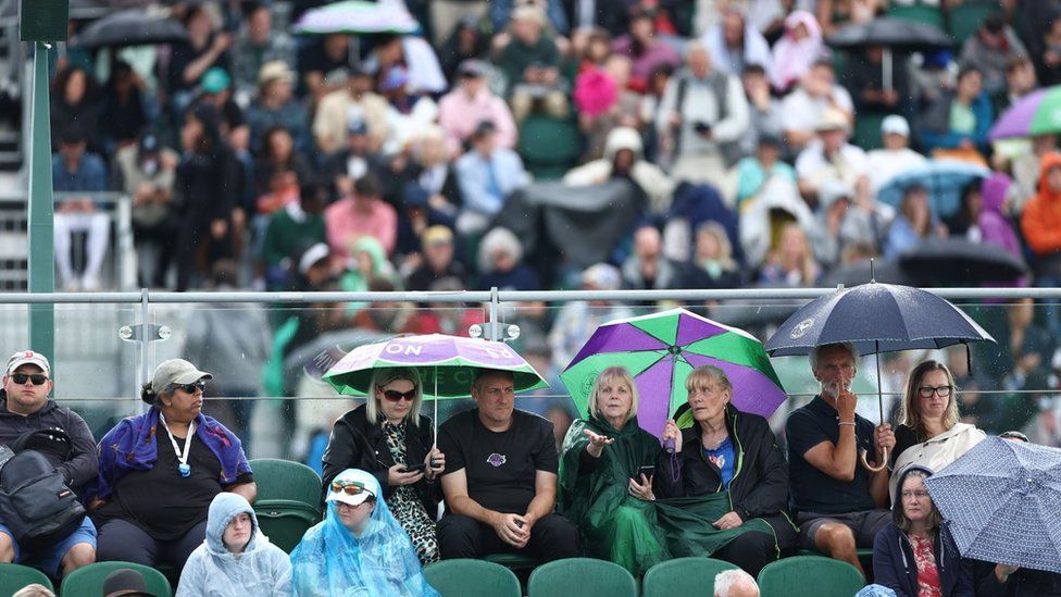 Wimbledon spectators beryllium   underneath their umbrellas