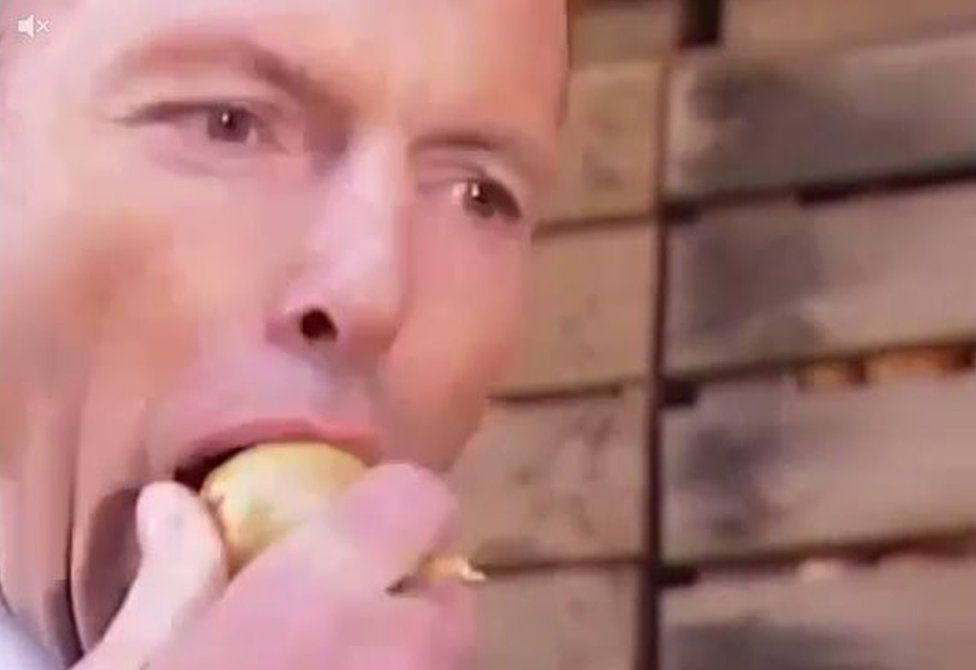 Tony Abbott bites into an onion