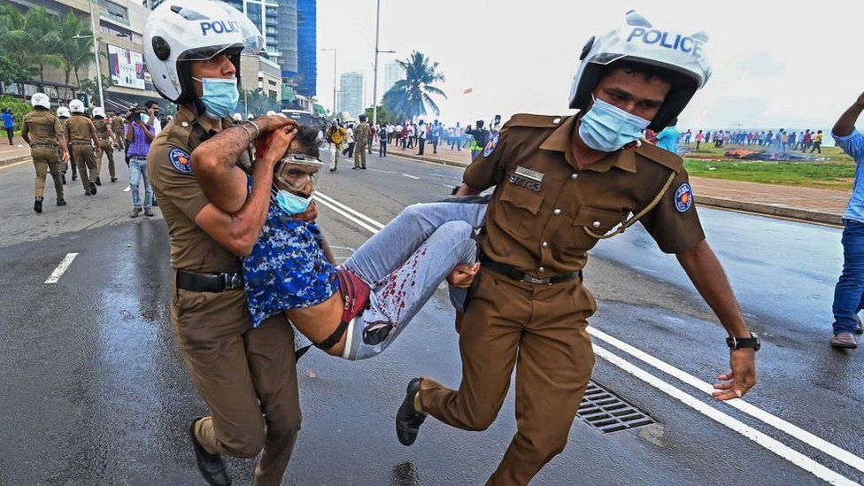 Policemen carry an injured man during a clash between government supporters and demonstrators outside the President's office in Colombo on May 9, 2022.
