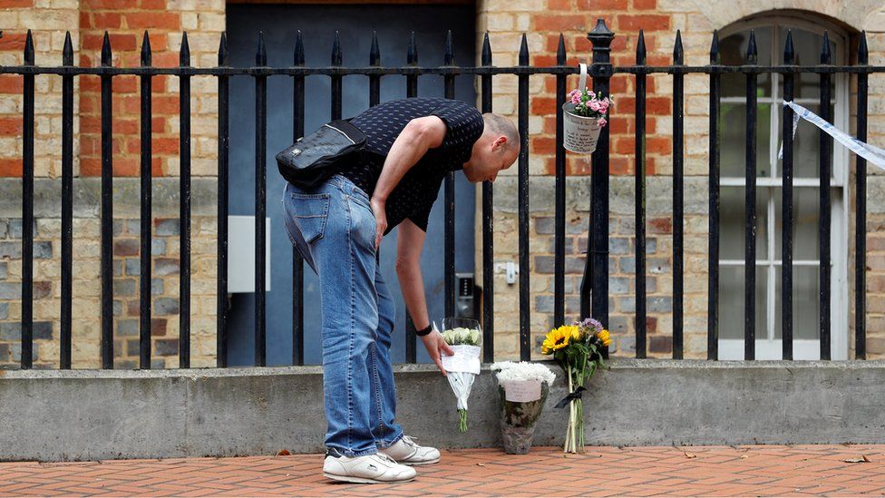 A man placing a floral tribute at Forbury Gardens in Reading