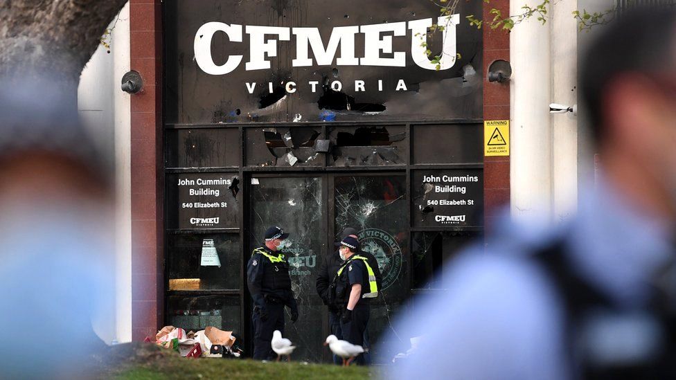 Police officers inspect a smashed façade at the Construction, Forestry, Maritime, Mining and Energy Union (CFMEU) headquarters in Melbourne, Victoria, Australia, 20 September 2021