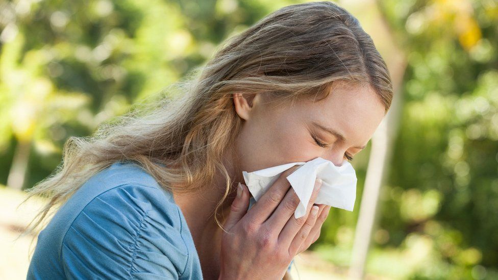 A woman holding a tissue to her nose