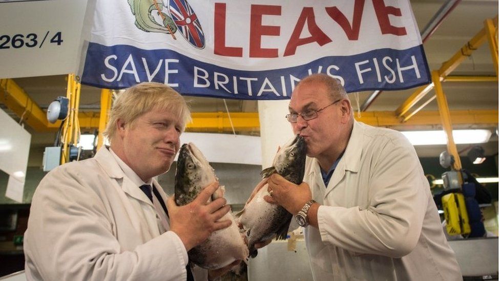 Boris Johnson (left) kisses a wild salmon as he is shown around Billingsgate Fish Market in London