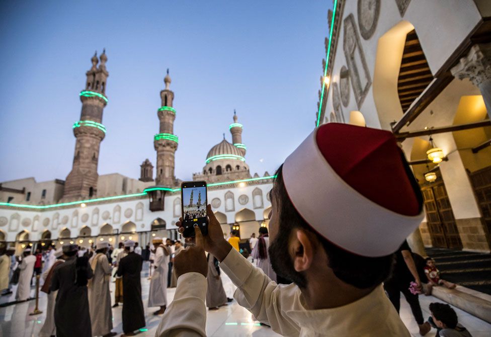 A worshipper from Afghanistan takes pictures during Eid al-Fitr prayers at al-Azhar mosque in Cairo