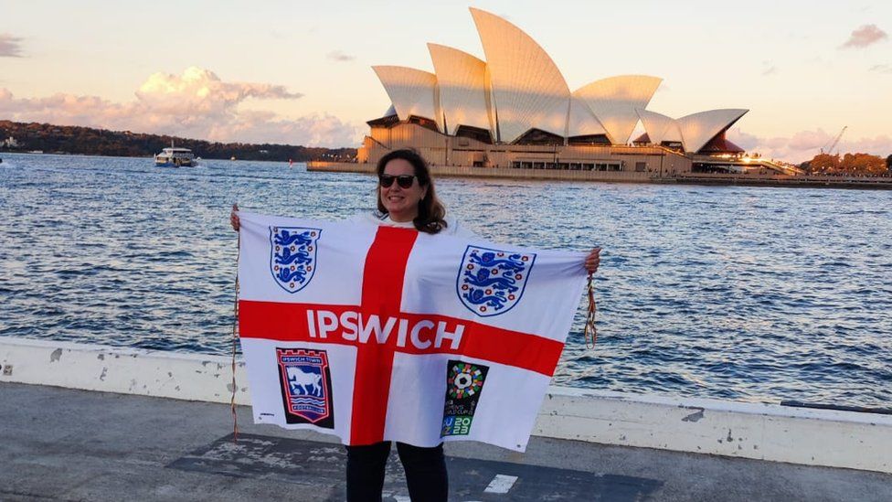 An Ipswich supporter holding a flag in front of the Sydney Opera House