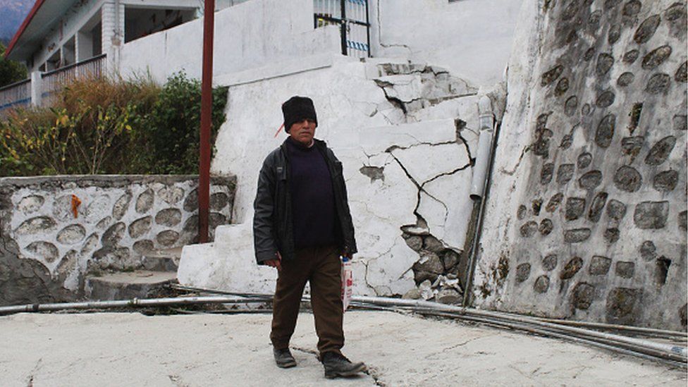 A resident walks past a house damaged with cracks in Joshimath, in Chamoli district of Uttarakhand on 11 January 2023