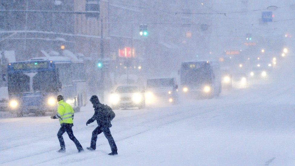 People cross a snow covered road on February 3, 2012 in Helsinki