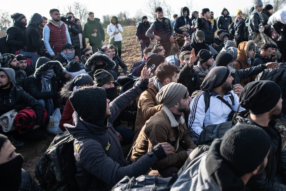 Refugees and migrants sit as they wait near Turkey's Pazarkule border crossing with Greece's Kastanies on 3 March