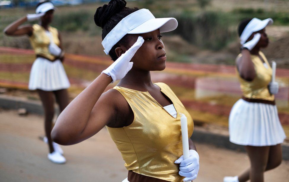 South African majorettes salute as they parade near the house of Winnie Mandela Soweto, Johannesburg, on April 8, 2018.