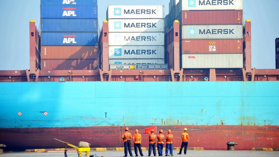Chinese workers look as a cargo ship is loaded at a port in Qingdao, eastern China's Shandong province on July 13, 2017.
