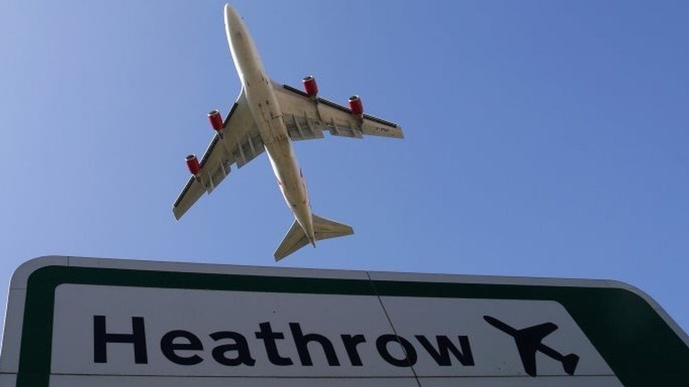A plane flying over a Heathrow sign