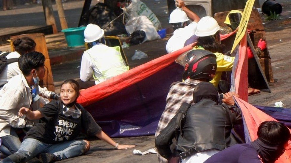 Protesters lie on the ground after police opened fire to disperse an anti-coup protest in Mandalay