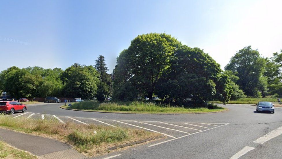 Boxgrove roundabout is shown with large trees in the middle, wide lanes and cars using it