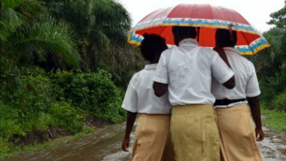 Three schoolgirls walks home in a countryside village of Sierra Leone on 12 July 2019.