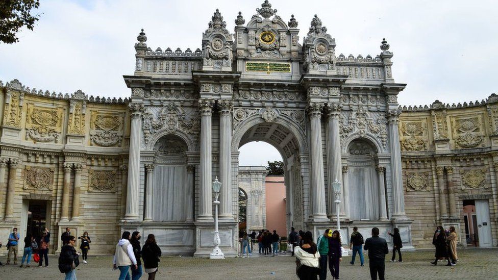 People walk near the a gate of Dolmabahce Palace, in Istanbul, Turkey, on 10 November 2021 (Altan Gocher/GocherImagery/Universal Images Group via Getty Images)