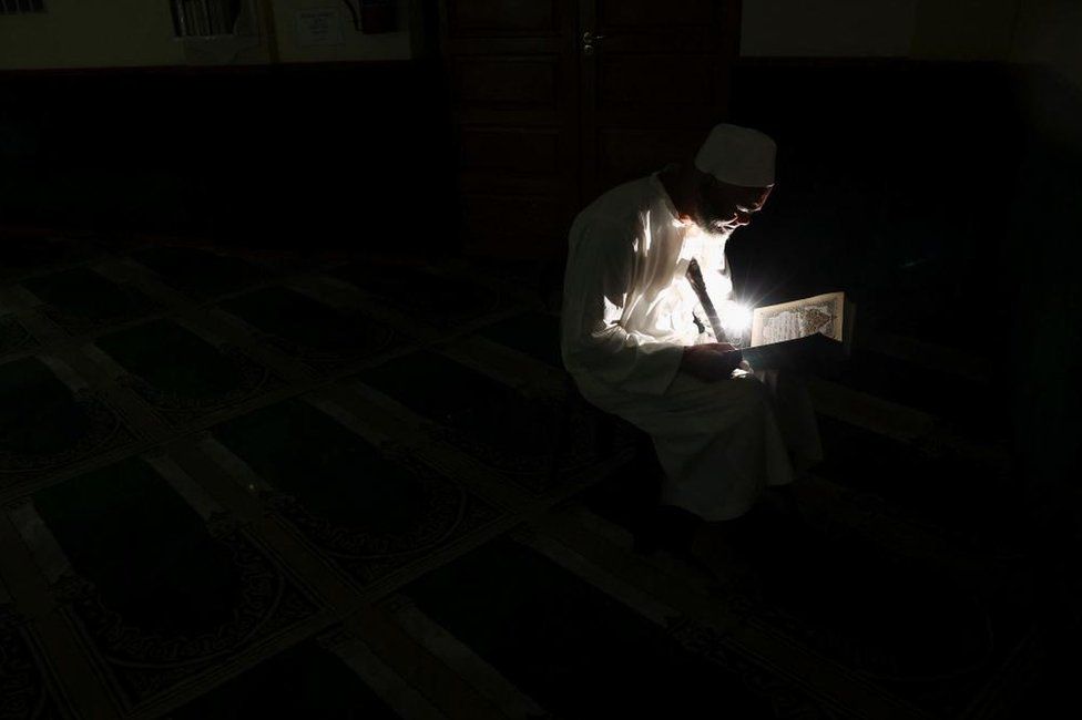 A Muslim man reads the Quran in a mosque and uses a mobile phone in Cape Town, South Africa, Wednesday 11 January 2023