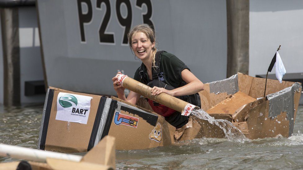 A woman rowing in a cardboard box