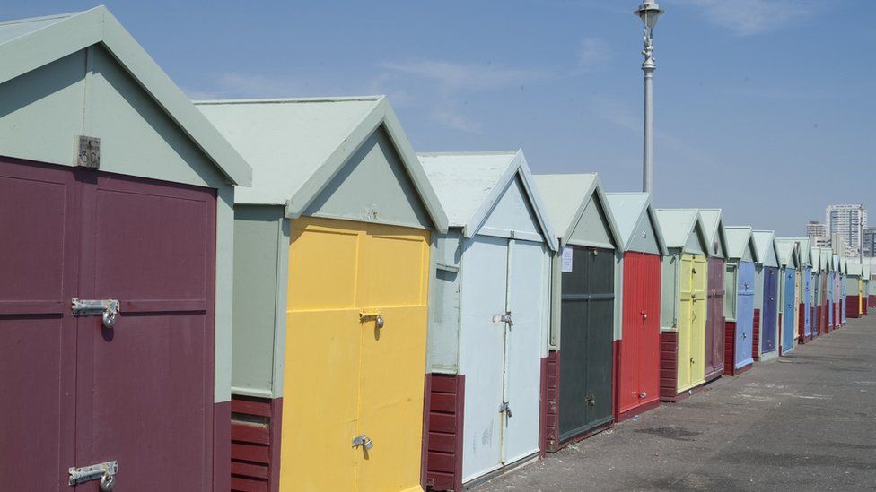 A long row of colourful beach huts on the seafront on the border between Brighton and Hove, East Sussex