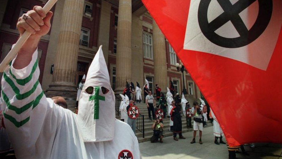 A member of the Ku Klux Klan waves a flag in Mercer, Pennsylvania, in August 1998