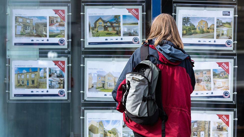 Человек смотрит на недвижимость в окне агента по недвижимости в Холмферте, Великобритания, 29 сентября 2022 г.