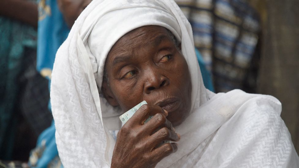 A woman dressed in white holds her identity card in Ede, Osun state, Nigeria
