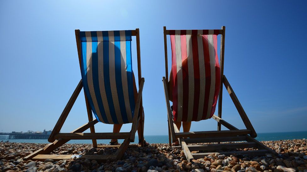 two people in deck chairs in the sun