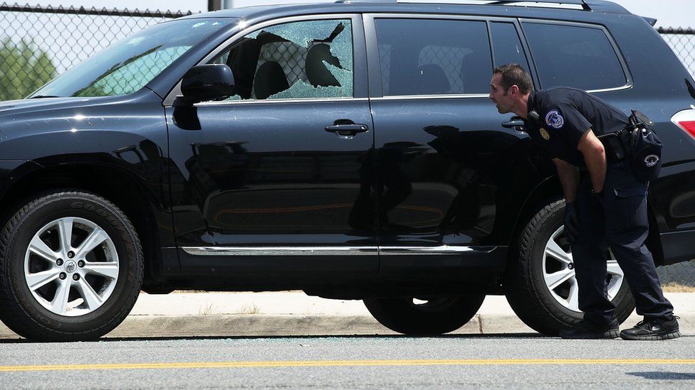 A member of the US Capitol Police observes a broken window on a vehicle at the scene of this morning's shooting at Eugene Simpson Stadium Park June 14, 2017 in Alexandria, Virginia