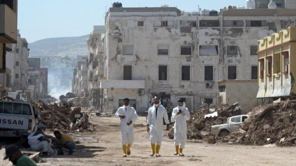 Men in hazmat suits walking through Derna