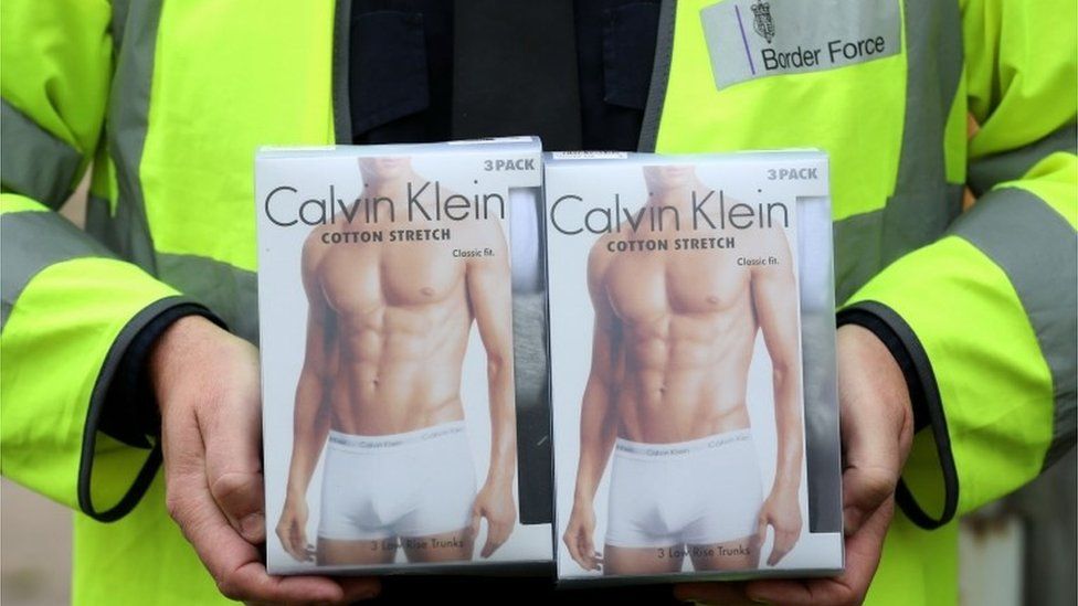 Border police officer holding boxes of Calvin Klein pants