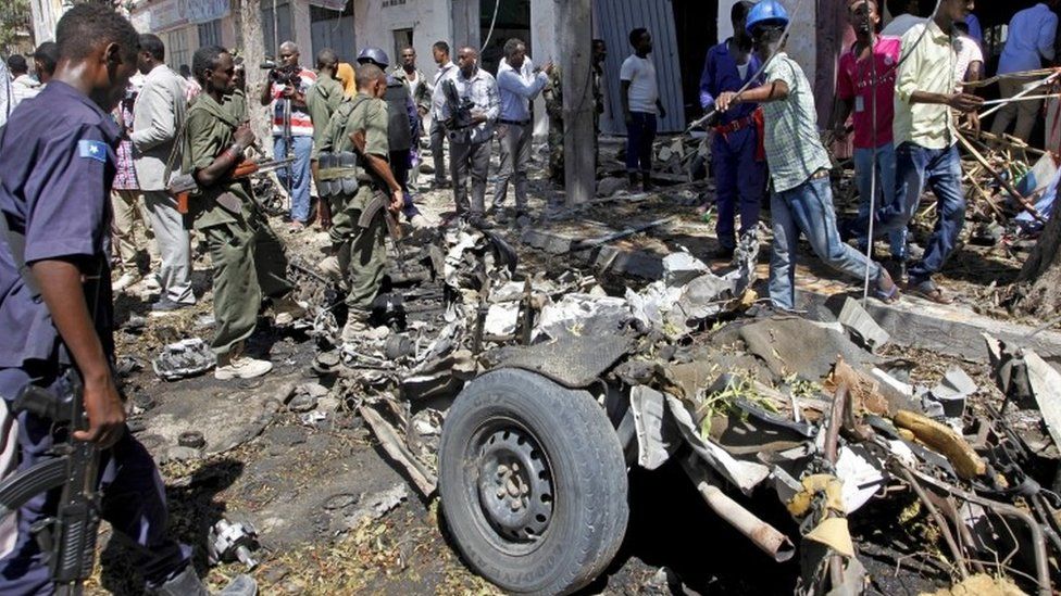 Security forces and others inspect the scene of a car bomb attack in the capital Mogadishu, Somalia Monday