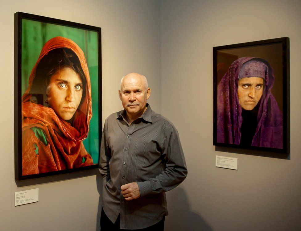 US photographer Steve McCurry poses next to his photos of the "Afghan Girl" Sharbat Gula in Hamburg, Germany on June 27, 2013.