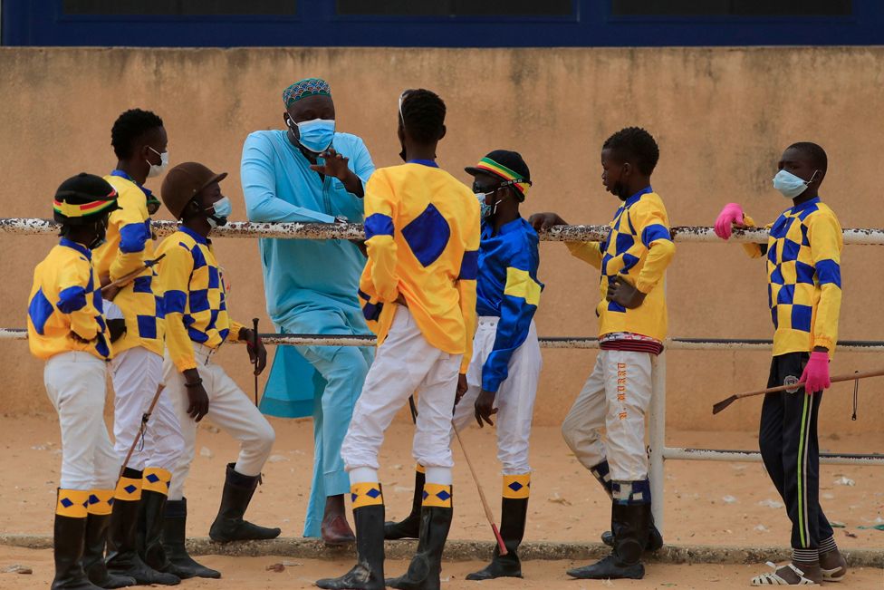 Adama Bao, a coach who owns the Lambafar stable, speaks to Fallou Diop and other jockeys before a race at in Thies, Senegal, 31 January 2021