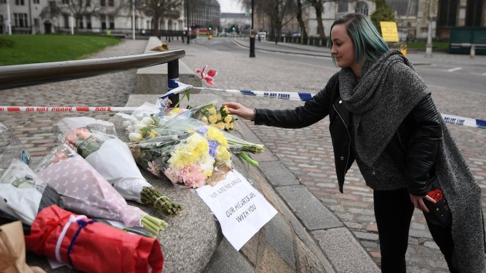 A woman lays flowers near the scene of the attack