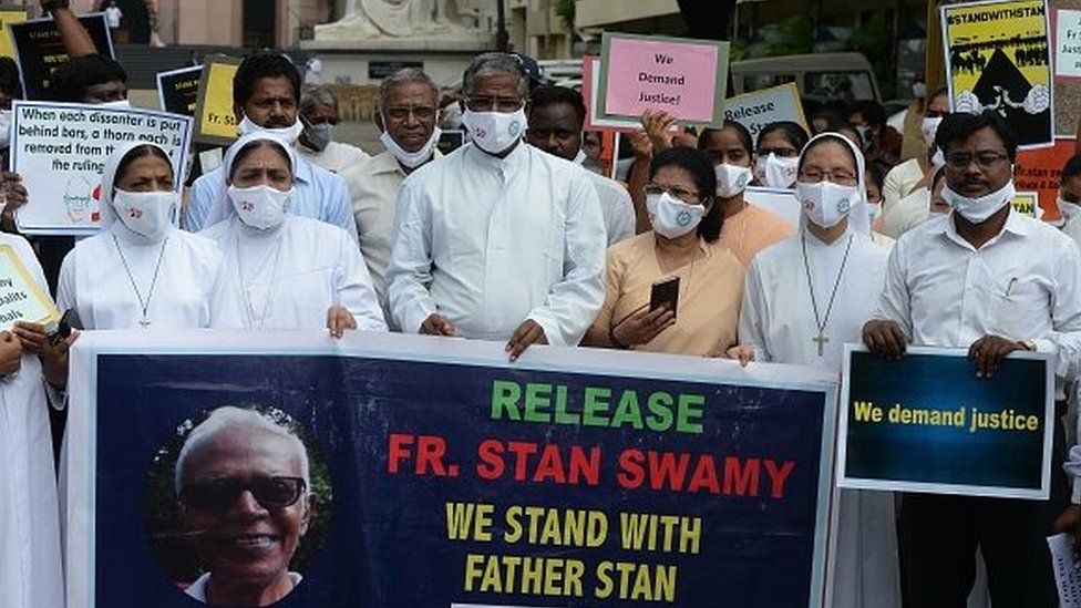 Католические священники и монахини держат знамя во время акции протеста против ареста иезуитского священника отца Стэна Свами в восточно-индийском штате Джаркханд.