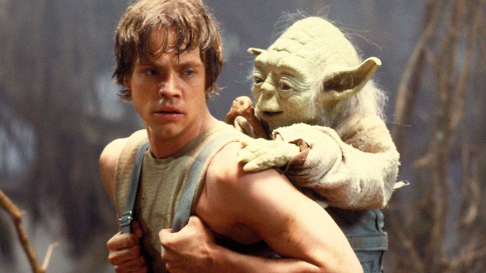 Mark Hamill as Luke Skywalker carrying Yoda through a swamp on Dagobah