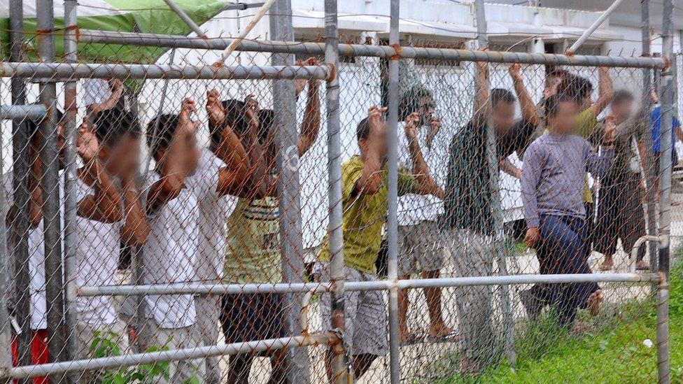 Asylum-seekers look through a fence at the Manus Island detention centre in Papua New Guine