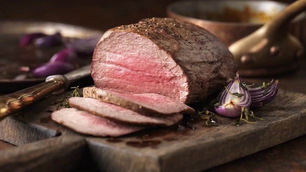 Christmas dinner. Chateaubriand steak cooked with a thick cut from the tenderloin filet, rare medium served with roasted onions, pepper and herbs - stock photo