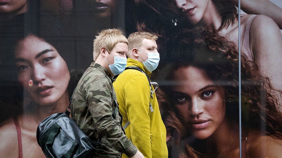 Shoppers wearing facemasks in front of a fashion advertisement in Glasgow, Scotland.