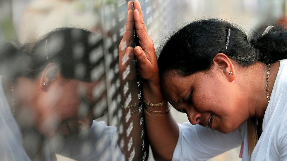 A family member of a Sri Lankan soldier who died in the civil war cries in front of a memorial