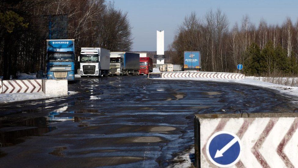 Trucks wait to pass Ukrainian border control in front of the Three Sisters monument at the border crossing between Ukraine, Russia and Belarus on 14 February 2022 in Senkivka, Ukraine