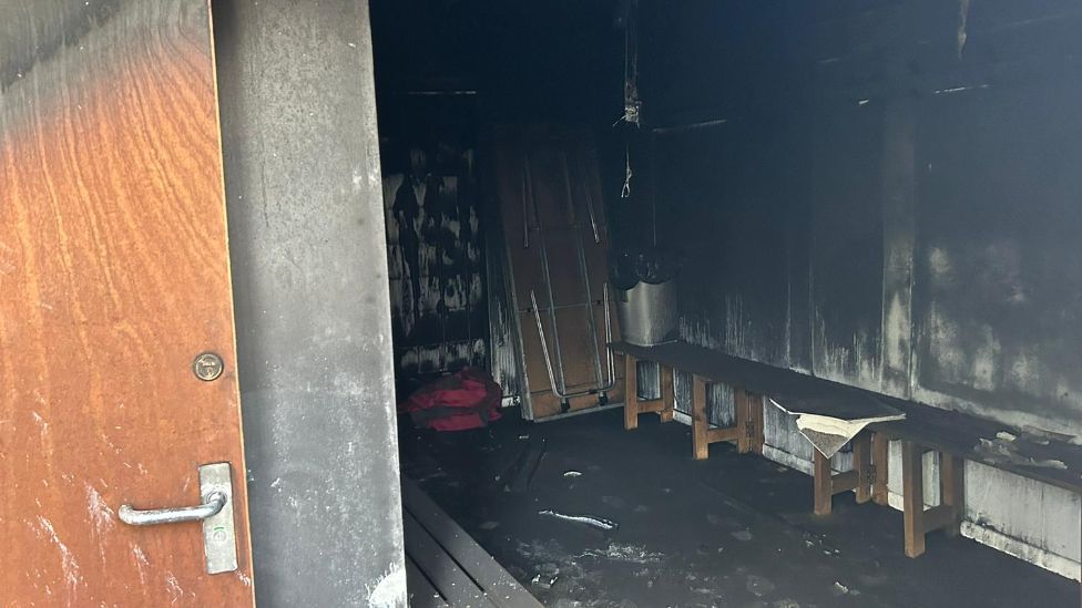 Changing rooms badly damaged by fire, with soot and scorch marks on the walls and floors