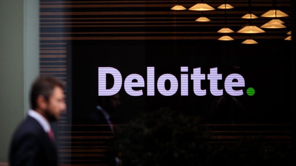 Мужчина проходит мимо офиса Deloitte