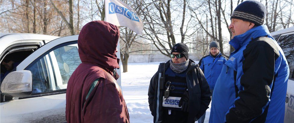 OSCE observers talk with a local resident woman (L) in Ukraine-controlled town of Avdiivka on 30 January