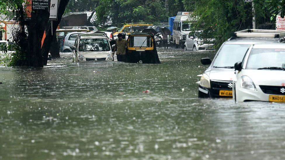 Vehicles drive through a flooded street during rain showers in Mumbai on July 5, 2022