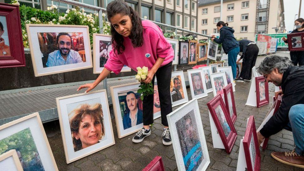 Syrian campaigner Wafa Mustafa sets up pictures of victims of the Syrian regime during a protest outside the court on June 4, 2020 in Koblenz