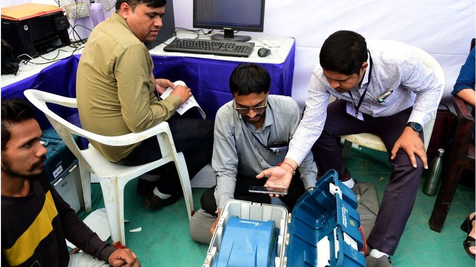 Сотрудники избирательных участков проверяют EVM (электронную машину для голосования) и другие материалы перед отправкой их в соответствующие пункты назначения в преддверии выборов в ассамблею штата Индиас-Гуджарат в Ахмадабаде 10 ноября 2022 года.